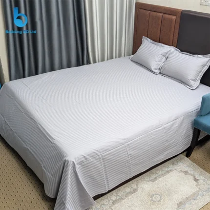 A moody, contemporary bedroom setup featuring an ash grey striped bed sheet paired with dark wood furniture and soft lighting.